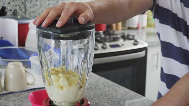 close-up of a man blending garlic in a blender in the kitchen at daytime in 4k