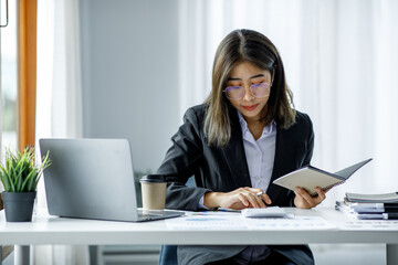 Portrait of young Asian businesswoman using write notebook laptop in home office. Beautiful girl at desk computer take home order. Startup business asia woman online sme telemarketing.