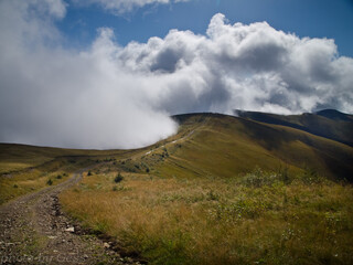 Clouds moving over green mountain range