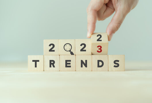 2023 trend concept. Hand flip wooden cube change year 2022 to 2023. Beautiful grey background, copy space. Used for banner in trend concept in new year for monitoring new business opportunities.