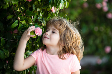 Spring child face. Close up portrait of a small blond child with spring flower. Funny kids in backyard. Kids close up face on blossom background. Children girl play in spring flowers.