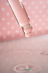A dripping pipette with a drop of cosmetics gel.