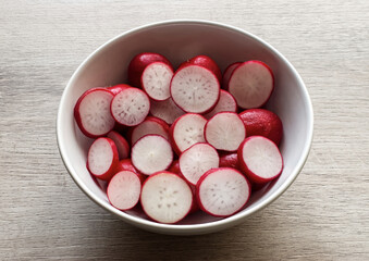 Red Radish slices in a bowl isolated on wooden background