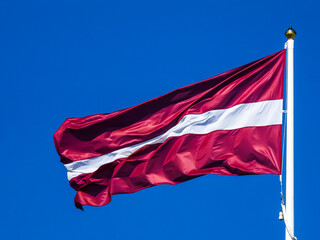 A flowing Latvian flag in the wind on a mast.
