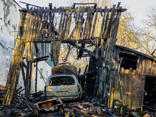 Fototapeta premium Burned barn, garage and car. Sunny spring day.
