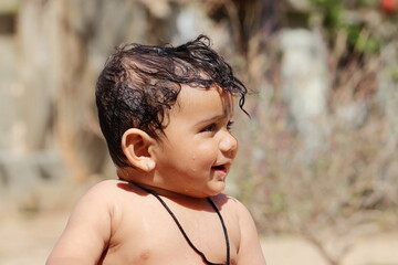 profile view Photo of A small cute Indian Hindu child expresses happiness while taking a bath with unclothed