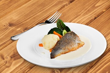 Fried fish with vegetable and salad on ceramic plate