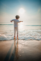 The boy jumped and played in the morning sea waves, still wearing his pajamas.