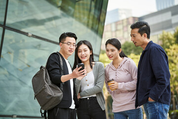 group of young asian people looking at cellphone together