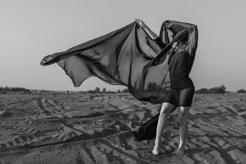 Woman in black dress dancing with flying fabric