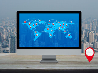 Map pin location button with connection line and world map on computer on table over city tower and...