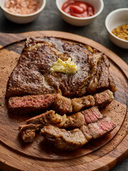 Medium rare Ribeye steak or beef steak on the wooden tray with herbs. Beef steaks with butter.