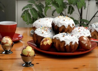 The concept of a festive homemade Easter food on the background of the kitchen with ratenie. Easter traditional buns with raisins and Easter eggs.