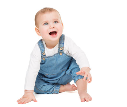 Happy smiling Baby in Jeans sitting over White isolated Background. Laughing little Child crawling looking up. Cheerful One Year Beauty Kid active playing