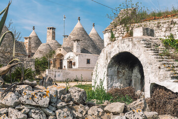 Group of beautiful Trulli or Trullo house, traditional Apulian dry stone hut with a conical roof and old dry stone walls in Puglia, Italy, with old stone outdoor oven or fireplace