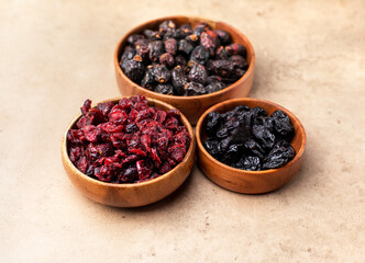 Healthy dried fruit, cranberry, prunes in a wooden bowl top view flatlay. Tasty food photo with copy space banner background.