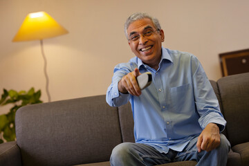 Senior man pointing while watching television at home