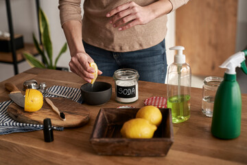 Unrecognizable person squeezing lemon juice to the bowl with DIY cleaning product