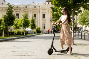 Young woman riding an electric scooter on a street © BGStock72