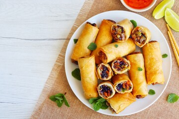 Crispy vegetarian spring rolls on plate with white wood table background.Top view.Copy space