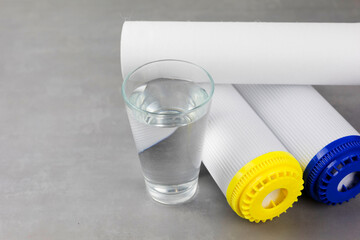 A glass of clean water next to the water purification filter. The concept of a household filtration...