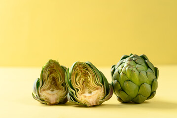 Obraz premium Half green artichoke on yellow background, Edible flower bud