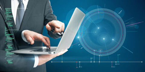 Close up of businessmen hands using laptop with futuristic blue HUD interface and glowing programming code on blurry blue background. Digital start up, teamwork, future and technology concept.