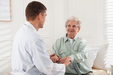 Fototapeta na wymiar Caregiver talking to senior woman in living room. Home health care service