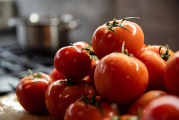Soczyste błyszczące pomidory w kuchni, w tle kuchenka gazowa z garnkiem