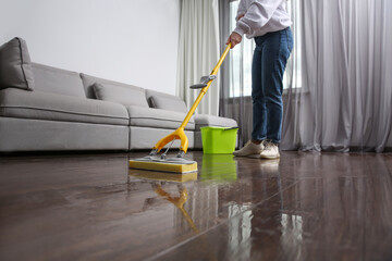 Fototapeta premium Woman cleaning parquet floor with mop indoors, closeup