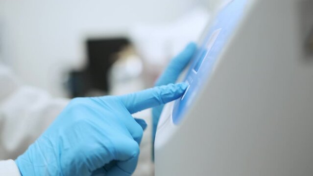 Woman sets parameters on the centrifuge for sample preparation. DNA, oncology marker analysis in clinical laboratory.