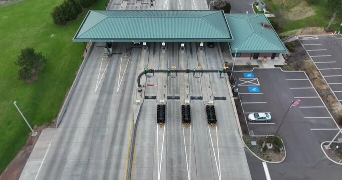 American flag at interstate toll plaza. EZ Pass electronically collects fare from vehicle drivers. Aerial view.