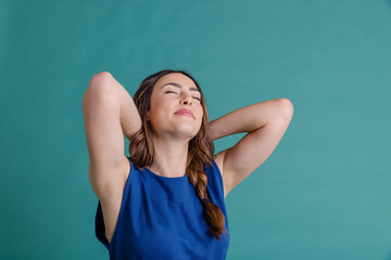 Smiling woman with hands behind head against blue background