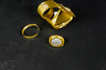 A tattered gold wine bottle capsule against a black background.