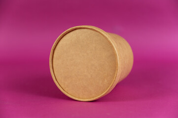Food to take away. Closed cylindrical paper container with lid opposite colored background. Brown food container for soup, ice cream, noodles or other food.