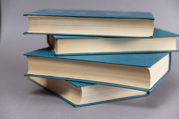 A few books in blue cover against a gray background. A group of hardcover books. Close-up.