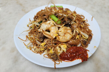 Stir-fried rice noodles with soy sauce, shrimps, bean sprouts, egg and sambal chili. Penang hawker food.