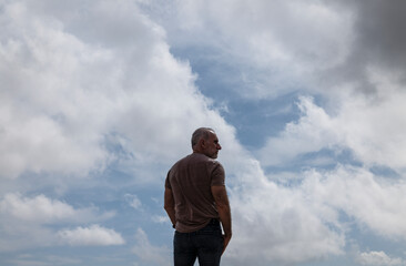 Rear view of adult man against cloudy sky