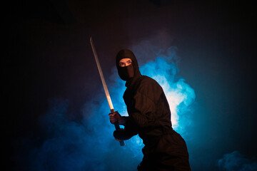 Medieval warrior assassin ninja with sword in aggressive pose in smoke