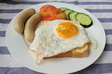 Healthy breakfast with sausages, eggs, cucumber, tomato and toasted bread.