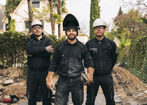 Smiling workers with grinders and work tool at construction site