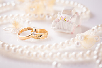 Wedding still life with golden rings and pearl necklace in white