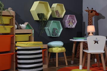 Stylish child room interior with modern furniture, toys and hexagon shaped shelves