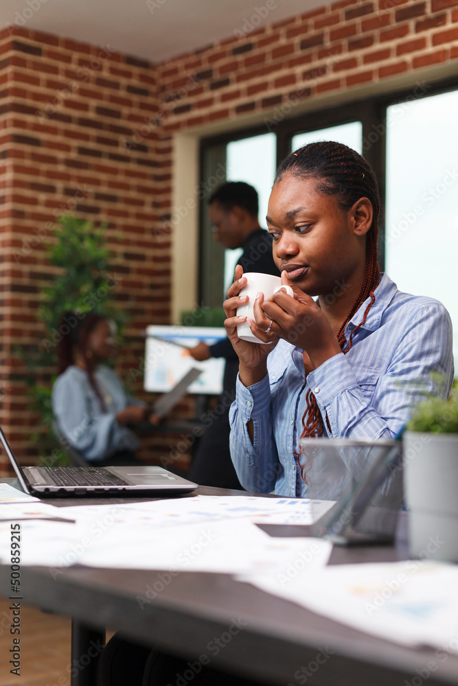 Poster marketing agency office worker having a cup of coffee while looking at work laptop. project manager 