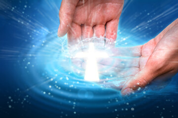 Cupped hands in water with glowing cross light. Sacrament of baptism religious theme concept.