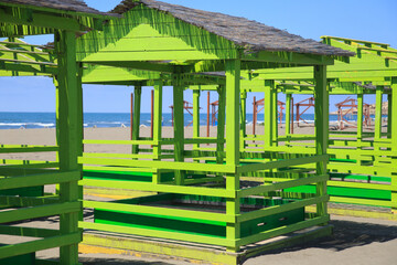 Plank arbors for relaxing in bright green on the beach on a bright sunny day.