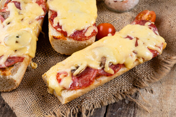 Homemade pepperoni pizza sandwich on a baguette on a wooden table.
