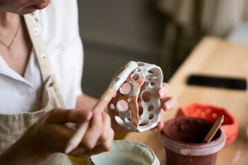 Woman painting ceramic bowl in workshop