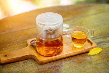 Teapots and glasses are placed on wooden trays with a natural backdrop.