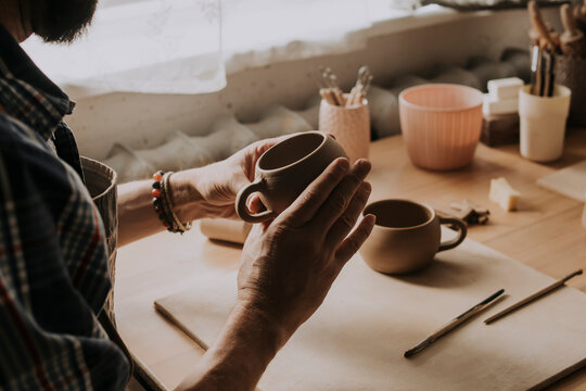 Young man examining earthen cup in workshop